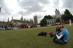 Tina and Melissa rest on the grass of Parliament Sqaure with the Houses of Parliament to the left and St. Margaret's Church to the right.